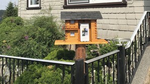 A house with a wooden deck, a birdhouse, and a metal railing. - Cozy vacation home with 2 separate living units in the Thuringian Forest (Suhl)