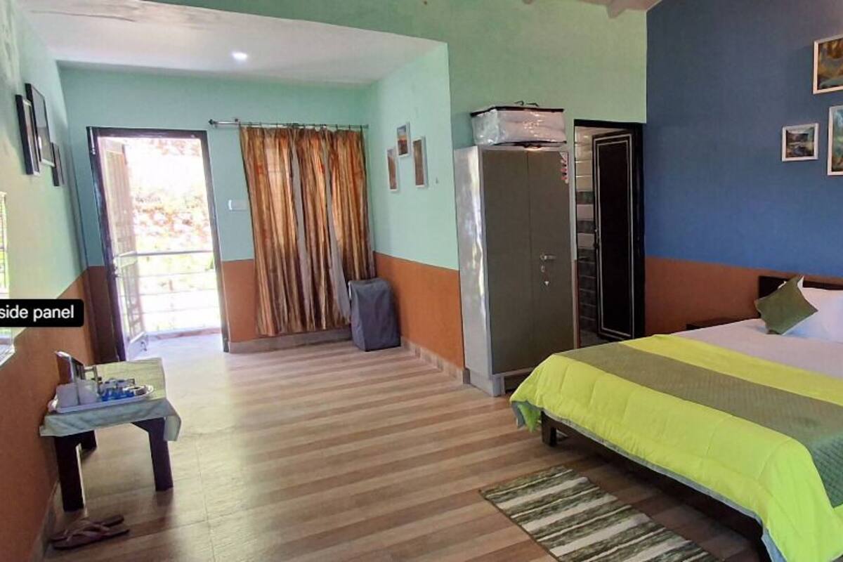 A hotel room with a bed, a desk, a wardrobe, and a view of the outdoors.