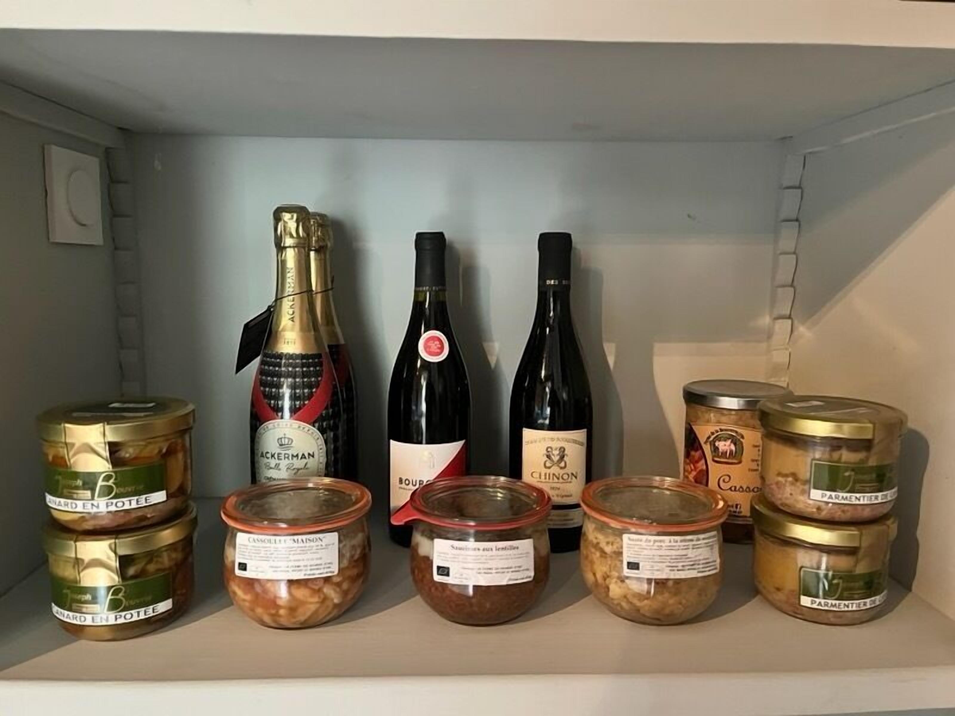 A shelf with various food items and two bottles of wine.