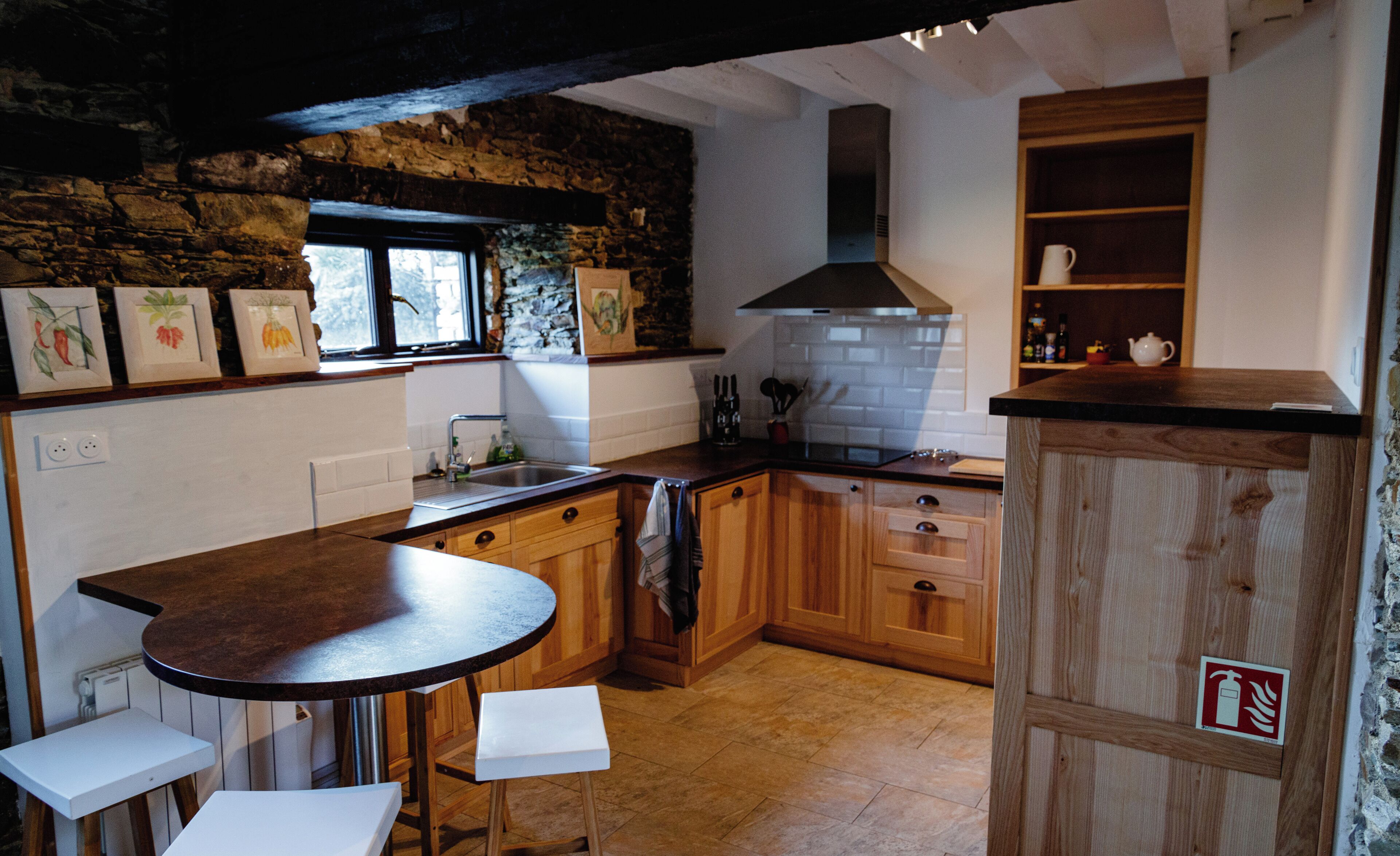Une cuisine avec des meubles de rangement en bois, un plan de travail noir et une fenêtre.