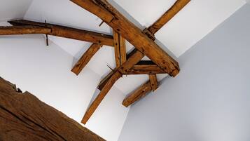 Estructura de techo de madera con vigas y una pared blanca.