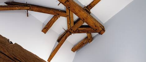 Een houten balkenplafond met een witte muur.