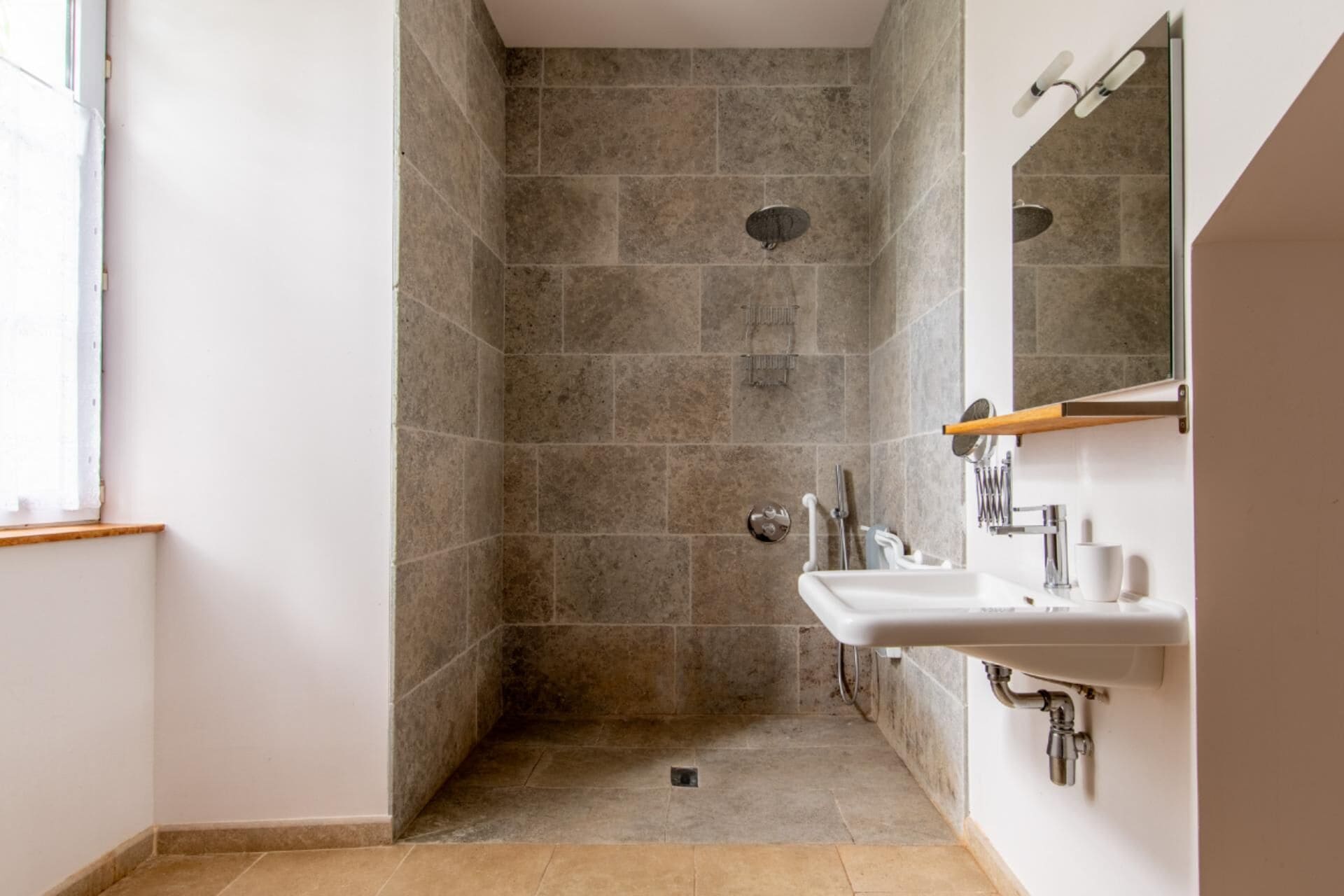 A modern bathroom with a shower, a sink, and a mirror.