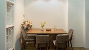 A dining area with a wooden table, four chairs, two pendant lights, and floral arrangements. - Quiet Family 6BR Home/Large Balcony/Street View/5' to Train St/Free Laundry (Hà Nội)