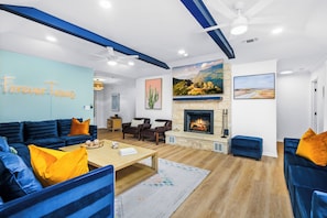 Ein modernes Wohnzimmer mit einer blauen Sofagarnitur, einem Kamin und einer Wand mit dem Schriftzug 'Forever Texas'.
