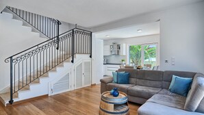 Ein modernes Wohnzimmer mit Treppe, einem grauen Sofa und einem Holztisch.