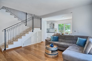 A modern living room with a staircase, a grey sofa, and a wooden coffee table.