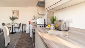 Eine moderne Küche mit Essbereich, Mülleimer, Toaster und einer Topfpflanze.