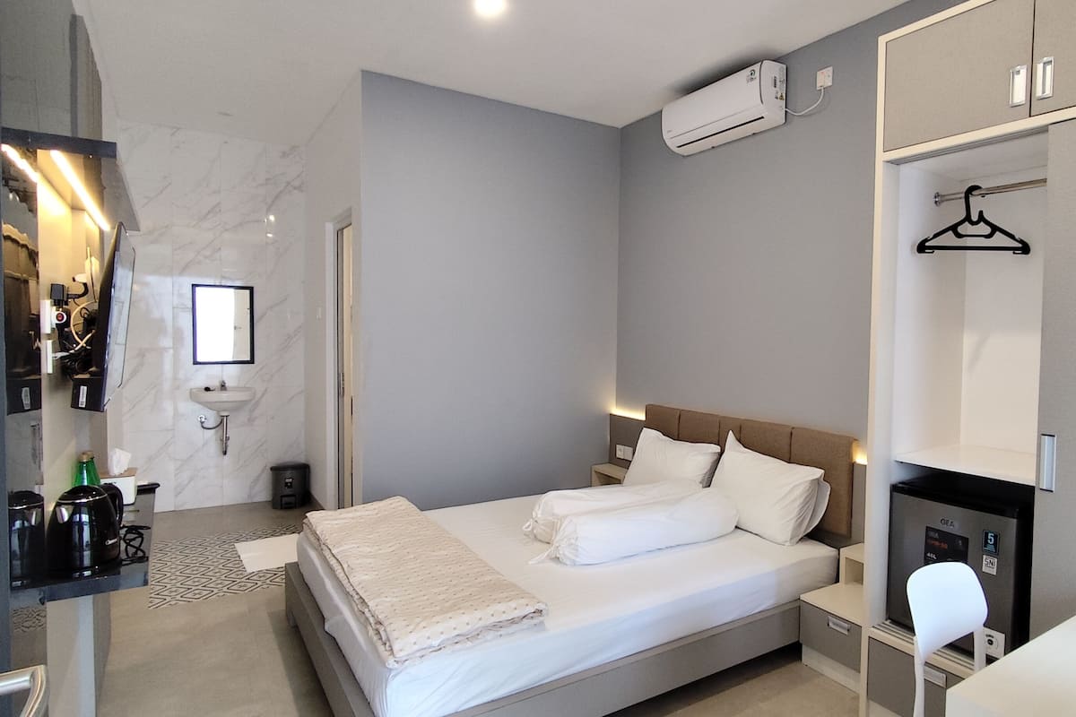 Une chambre d’hôtel moderne, dotée d’un grand lit, de tables de chevet, d’un bureau et d’une chaise.