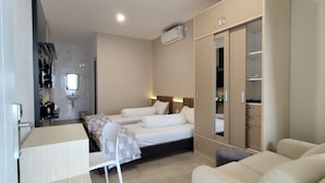 Une chambre d’hôtel moderne équipée d’un lit, d’un bureau, d’une chaise, d’une armoire et d’une salle de bain avec un lavabo et un miroir.