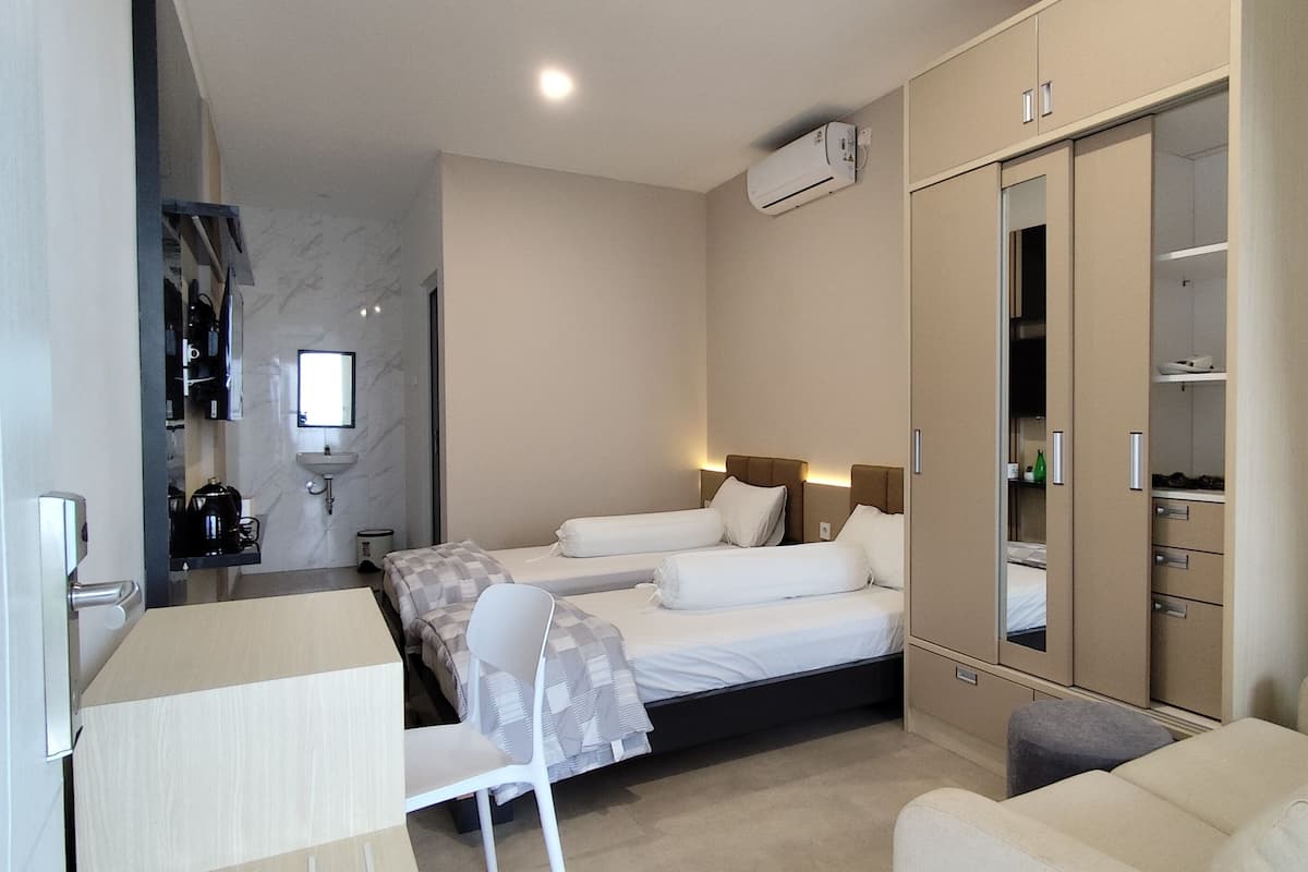 Une chambre d’hôtel moderne équipée d’un lit, d’un bureau, d’une chaise, d’une armoire et d’une salle de bain avec un lavabo et un miroir.