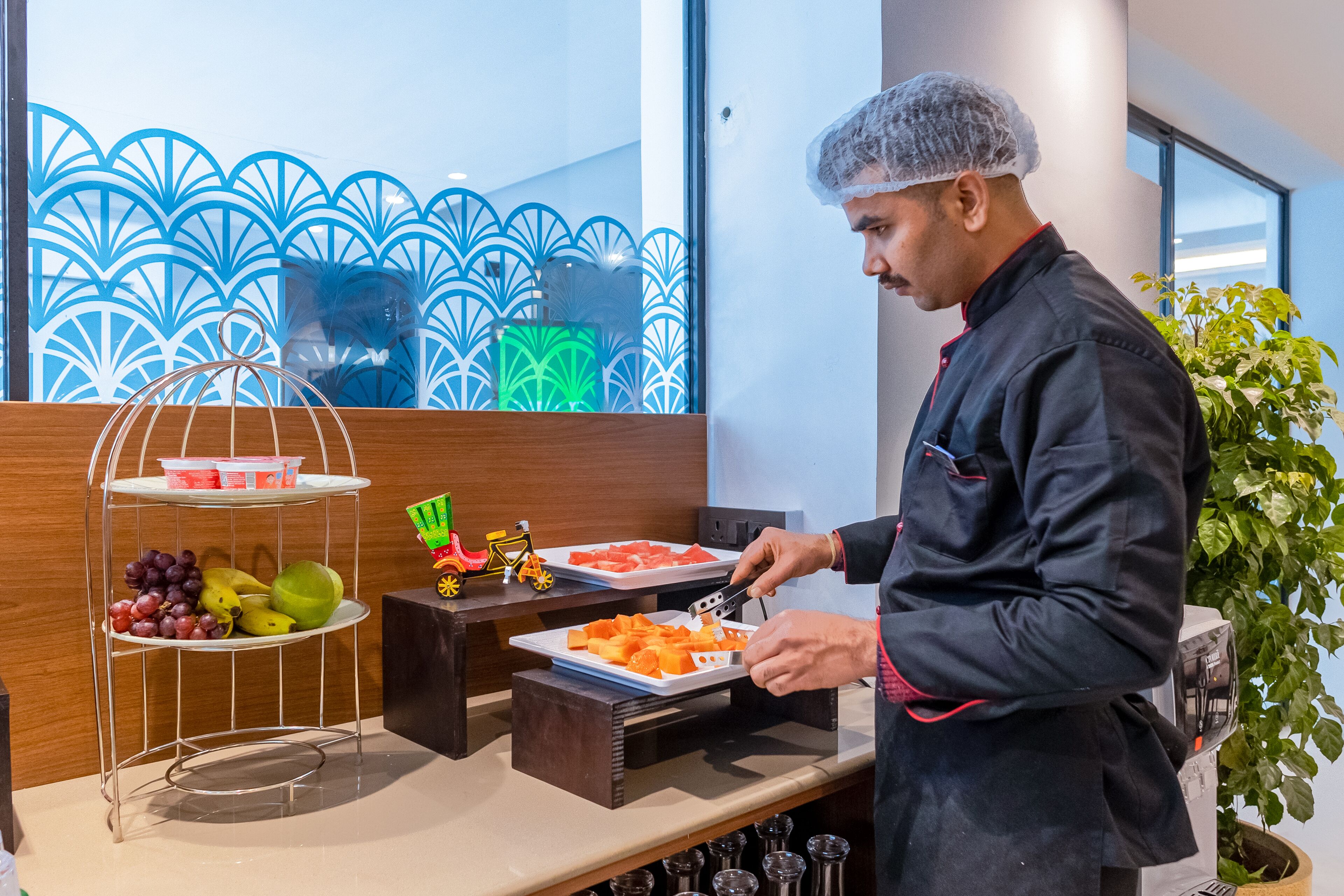 A buffet setup with various fruits and a person serving food.