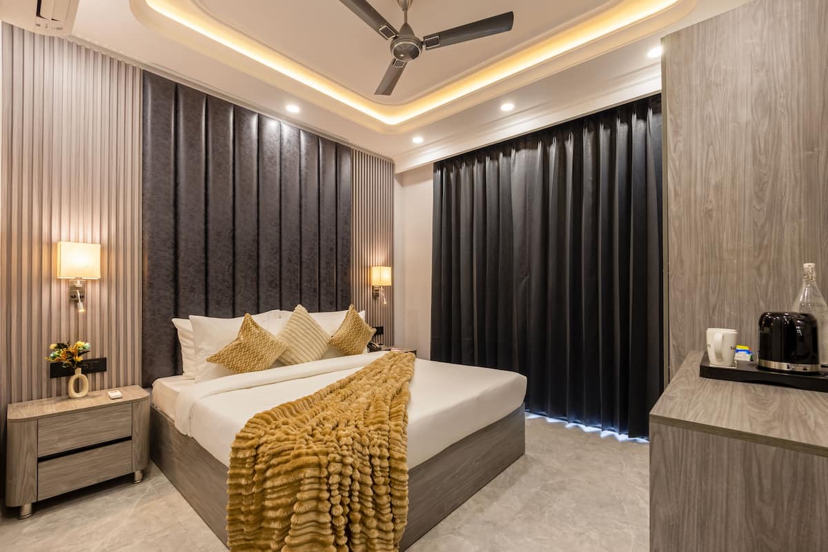 A modern hotel room with a large bed, bedside tables, a ceiling fan, and a nightstand with a lamp.