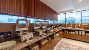 A buffet setup with various food stations, a wooden panel wall, and a patterned rug. - Saltstayz Premier Near Sector 44 Corporate Hub (Gurugram)