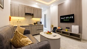 A modern living room with a sofa, coffee table, and a mounted TV. - Saltstayz Premier Near Sector 44 Corporate Hub (Gurugram)