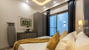 A modern hotel room with a bed, a desk with a computer, a painting on the wall, and a window with curtains. - Saltstayz Premier Near Sector 44 Corporate Hub (Gurugram)