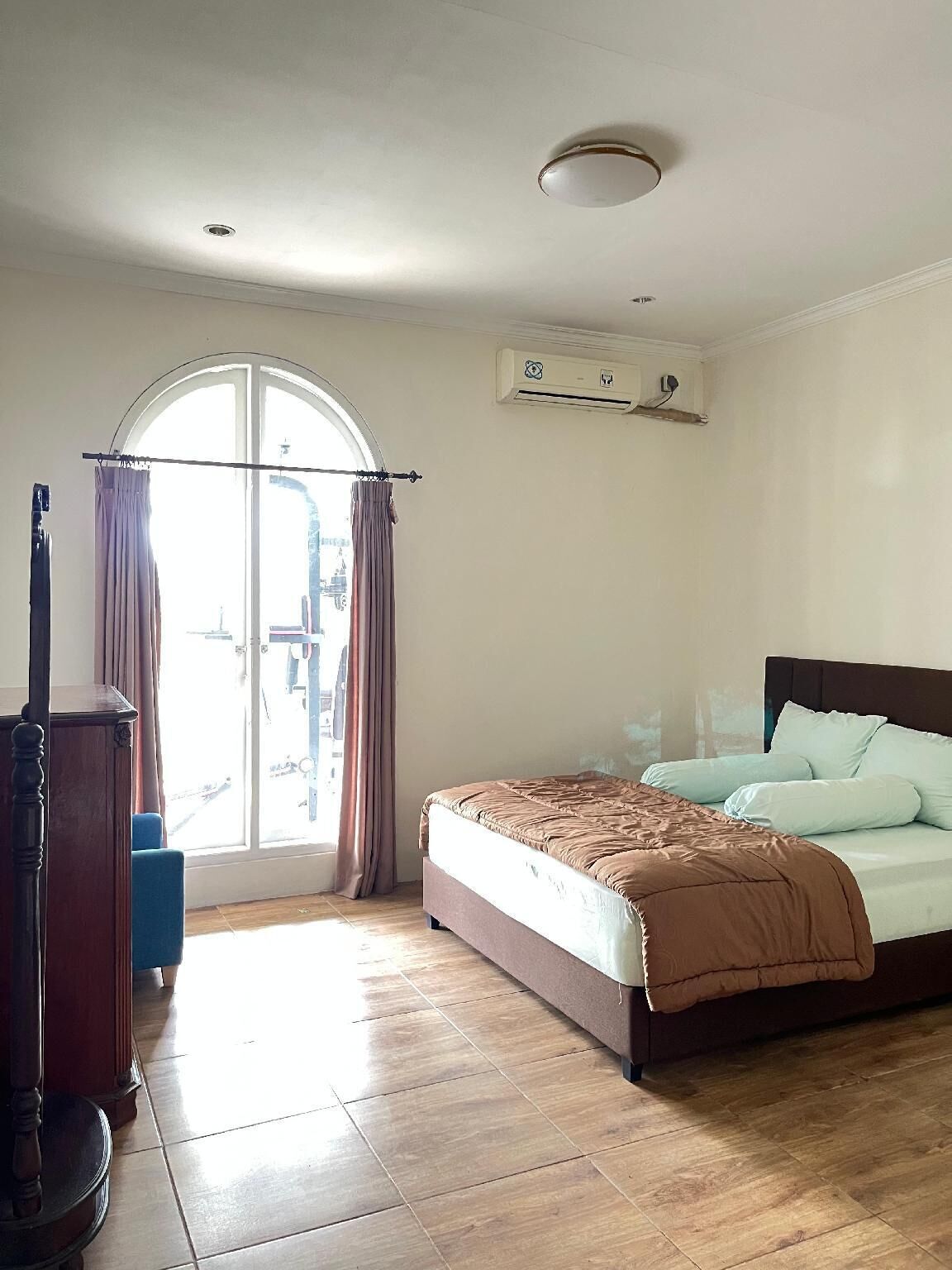 A bedroom with a bed, a window with curtains, a ceiling fan, and an air conditioning unit.