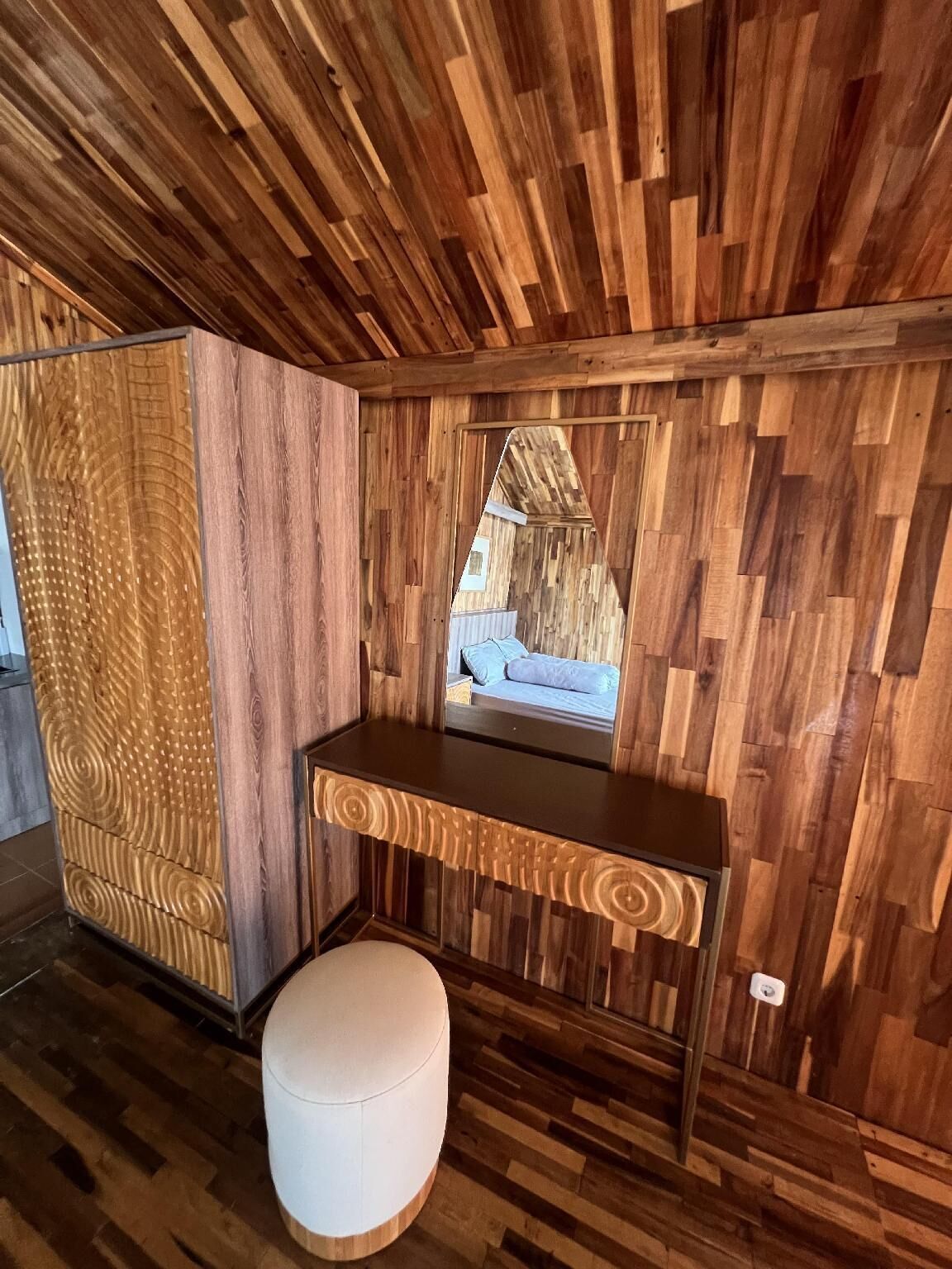 A room with a wooden wall panel design, a built-in bench, and a small stool.