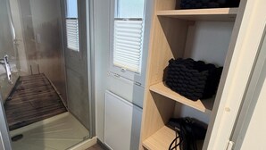 Un baño pequeño con ducha, inodoro y estantes para guardar objetos.