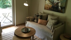 A living room with a sofa, a coffee table, a floor lamp, and a painting on the wall.