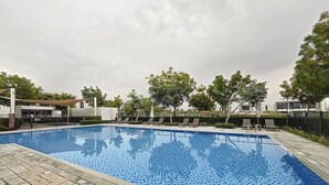 Ein rechteckiger Pool mit Fliesenrand, umgeben von einer gepflasterten Liegefläche.