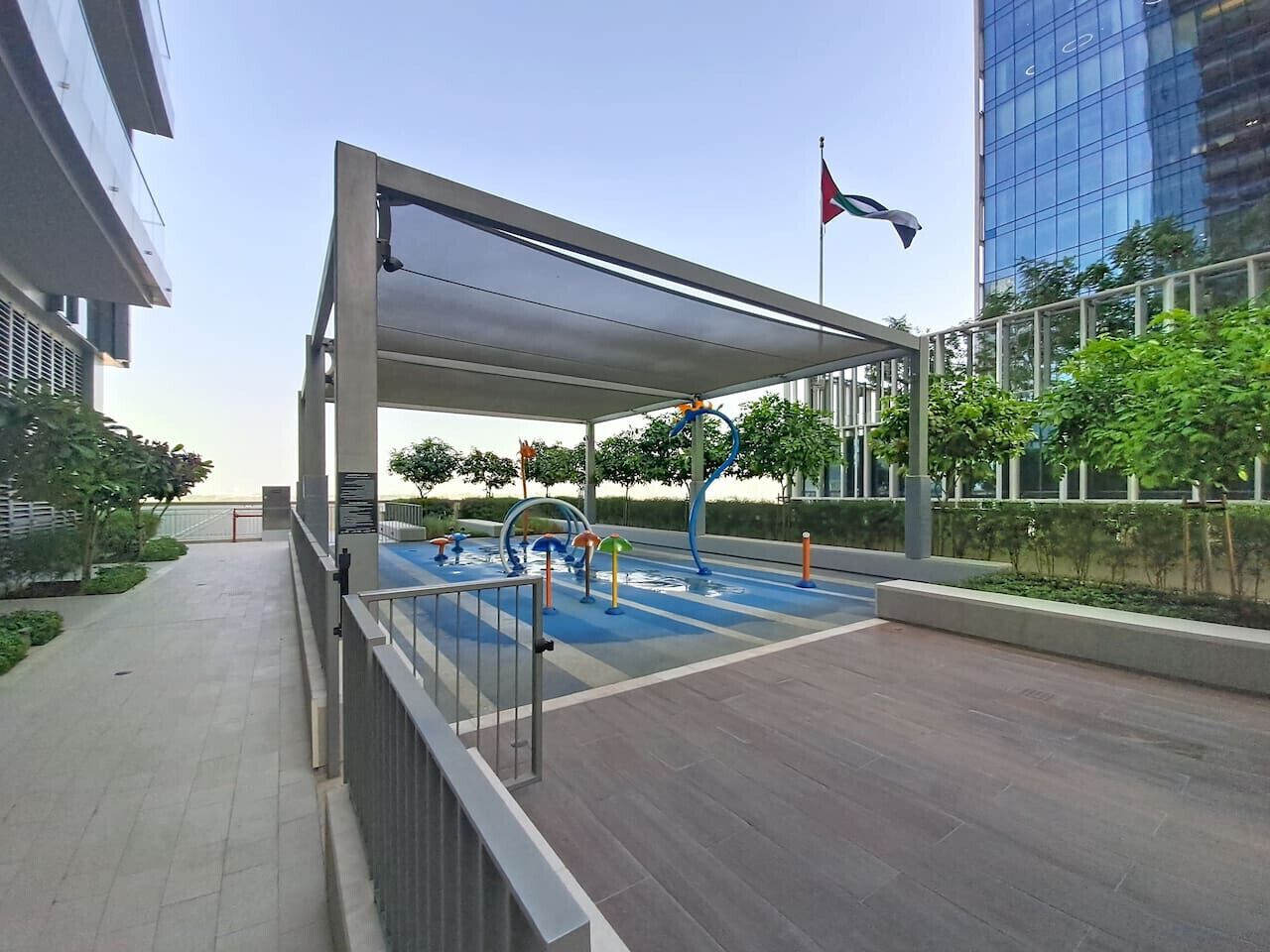 An outdoor area with a covered seating area, a water play area, and a flag.
