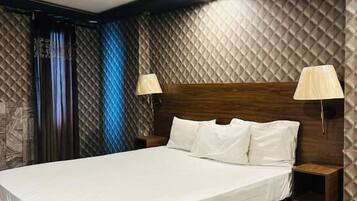 Habitación de hotel moderna con una cama grande, dos mesitas de noche y un diseño de techo original.