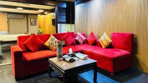 Un sofá rojo con varios cojines, una mesa de centro de madera y una pared con listones verticales de madera.