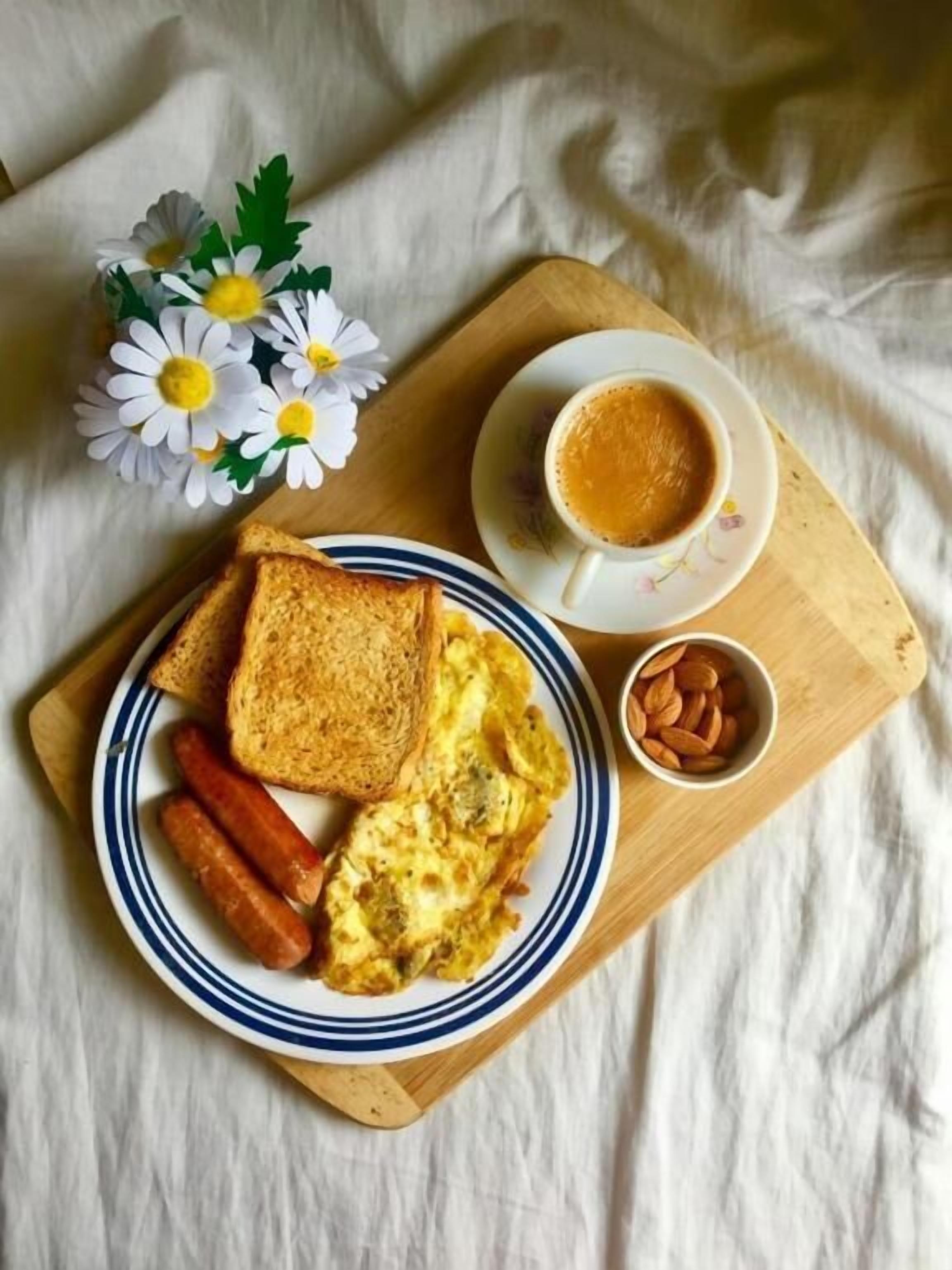 Un plato de desayuno con tostadas, salchichas y huevos revueltos sobre una tabla de madera.