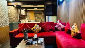 Una habitación de hotel moderna con un sofá rojo, una mesa de centro de madera y un jarrón estampado.