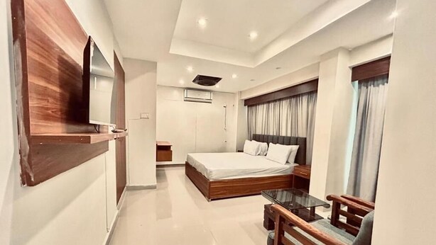 Una habitación de hotel moderna con una cama grande, un escritorio pequeño y un televisor montado en la pared.