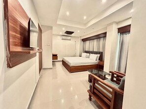 A modern hotel room with a large bed, a small desk, and a TV mounted on the wall. - Hotel Seaview (Karachi)