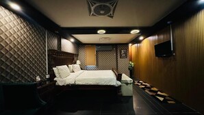 Un dormitorio moderno con una cama grande, un televisor de pantalla plana en la pared y un ventilador de techo.