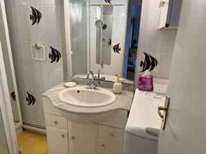 Een badkamer met een wastafel, spiegel en decoratieve tegels met vismotieven.