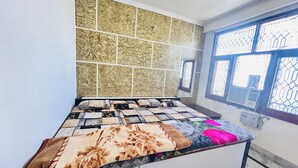 A bedroom with a bed, a window with bars, and a wall with a patterned tile design. - Superb 9-bedroom house with AC in charming Vrindavan (Vrindavan)