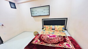 A bedroom with a bed, a headboard, a wall-mounted shelf, and a small window. - Superb 9-bedroom house with AC in charming Vrindavan (Vrindavan)