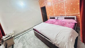 A bedroom with a bed, a ceiling fan, a wall with a butterfly pattern, and a door. - Superb 9-bedroom house with AC in charming Vrindavan (Vrindavan)