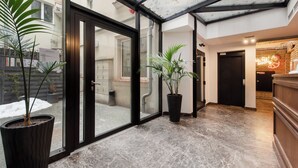 A modern hotel lobby with glass doors, potted plants, and a marble floor. - Sun & Snow Rakowicka Residence (Kraków)