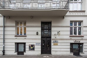Ein Gebäude mit einer schwarzen Tür, einem Schild mit dem Schriftzug 'Wiktor' und einem Poster an der Wand.