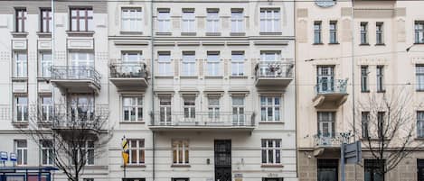 Un edificio a più piani con un ingresso centrale, balconi e un negozio a livello strada.