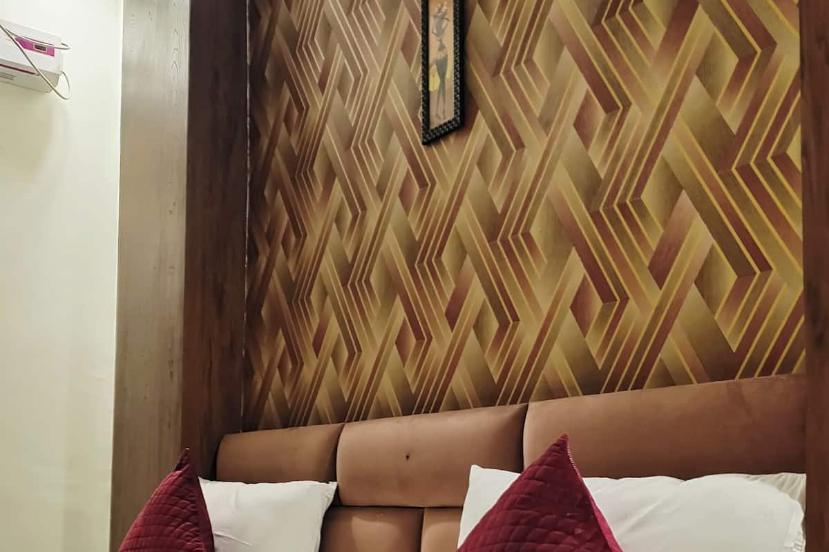 A bed with a wooden headboard, white bedding, and two red pillows.