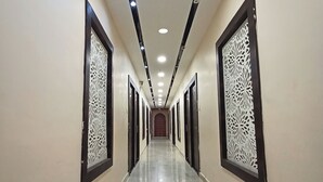 Un largo y estrecho pasillo con suelo pulido, bordeado por paredes con paneles decorativos y una serie de puertas a un lado.