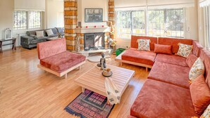 A spacious living room with a fireplace, red sofas, a coffee table, and a patterned rug. - Rida Sultan Konağı (Foca)