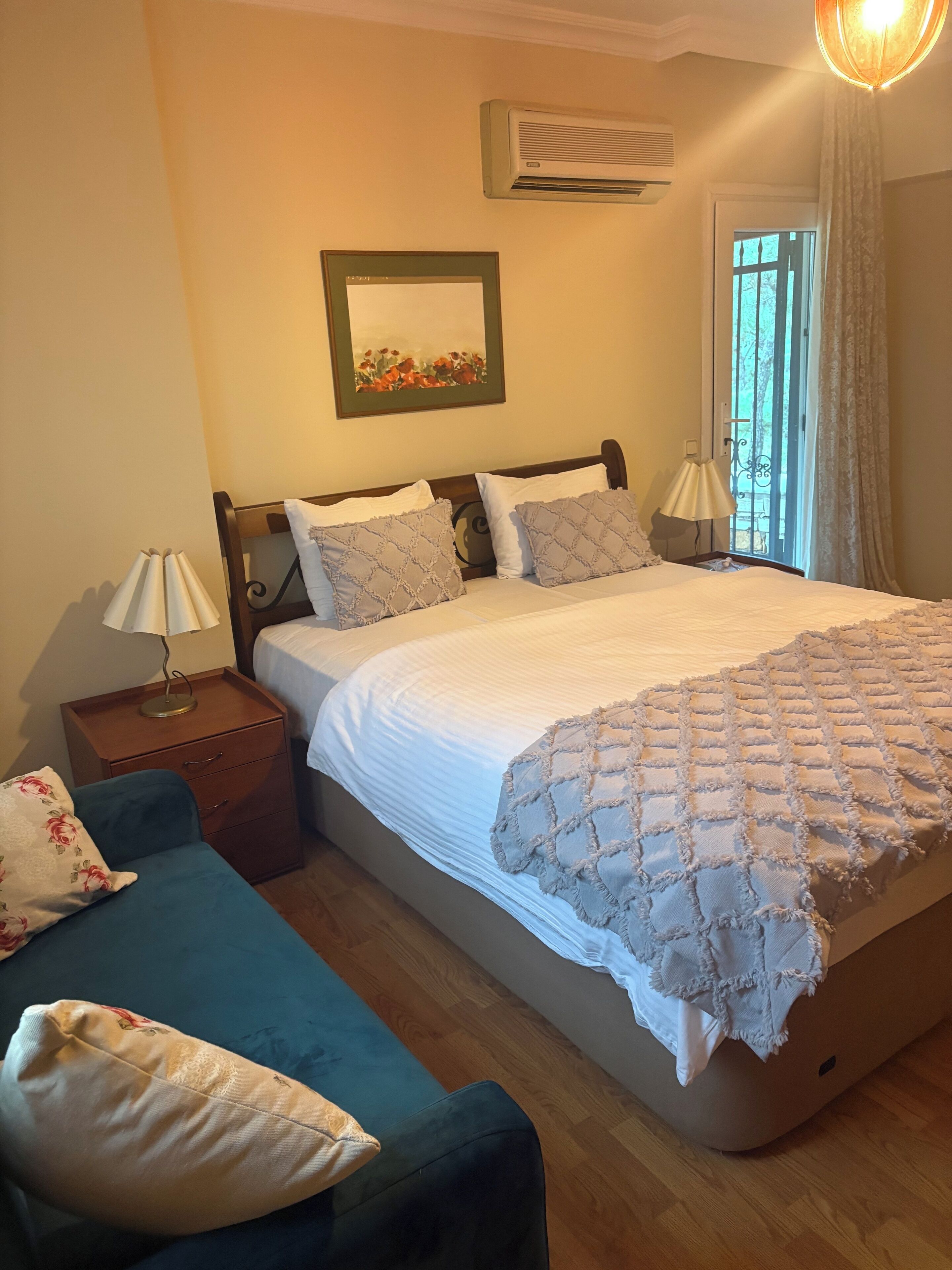 A bedroom with a bed, a nightstand, a lamp, a chair, and a window with curtains.