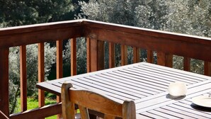 A wooden deck with a table and chairs, overlooking a forested landscape. - Rida Sultan Konağı (Foca)