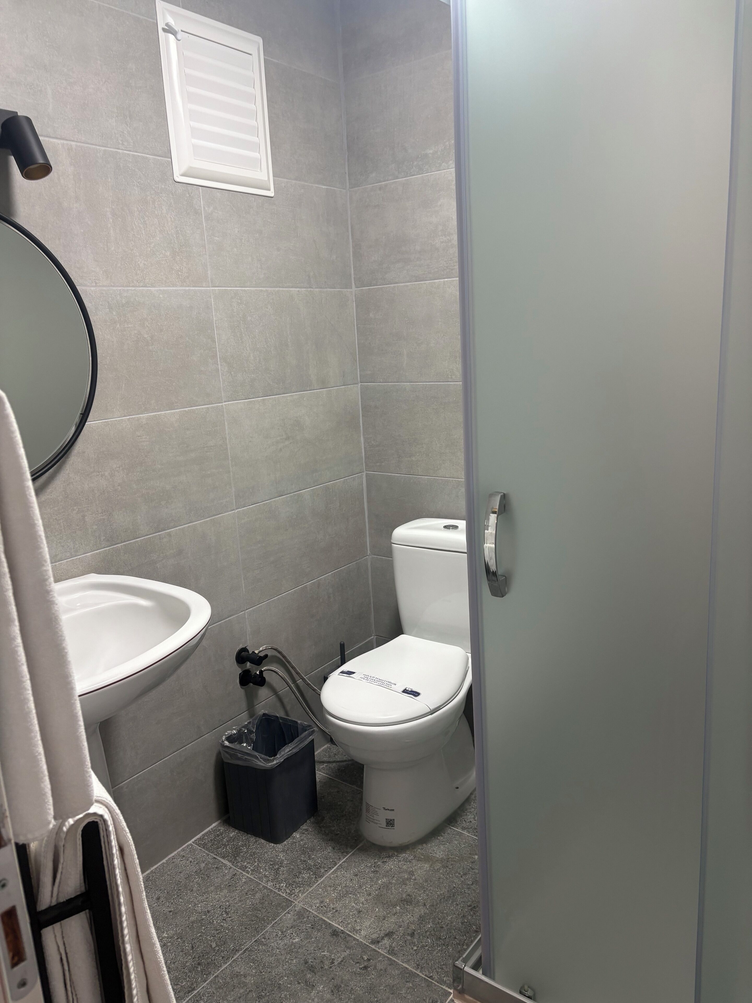 A small bathroom with a toilet, sink, and mirror.