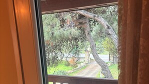 A view through a glass door to an outdoor area with a wooden bench and a pathway. - Rida Sultan Konağı (Foca)