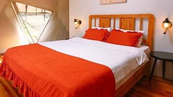 A bedroom with a wooden bed, red bedding, and a sloped ceiling.