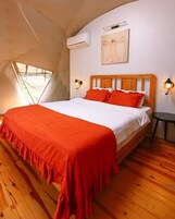 Ein Schlafzimmer mit einem Holzbett, roter Bettwäsche und einer geneigten Decke.
