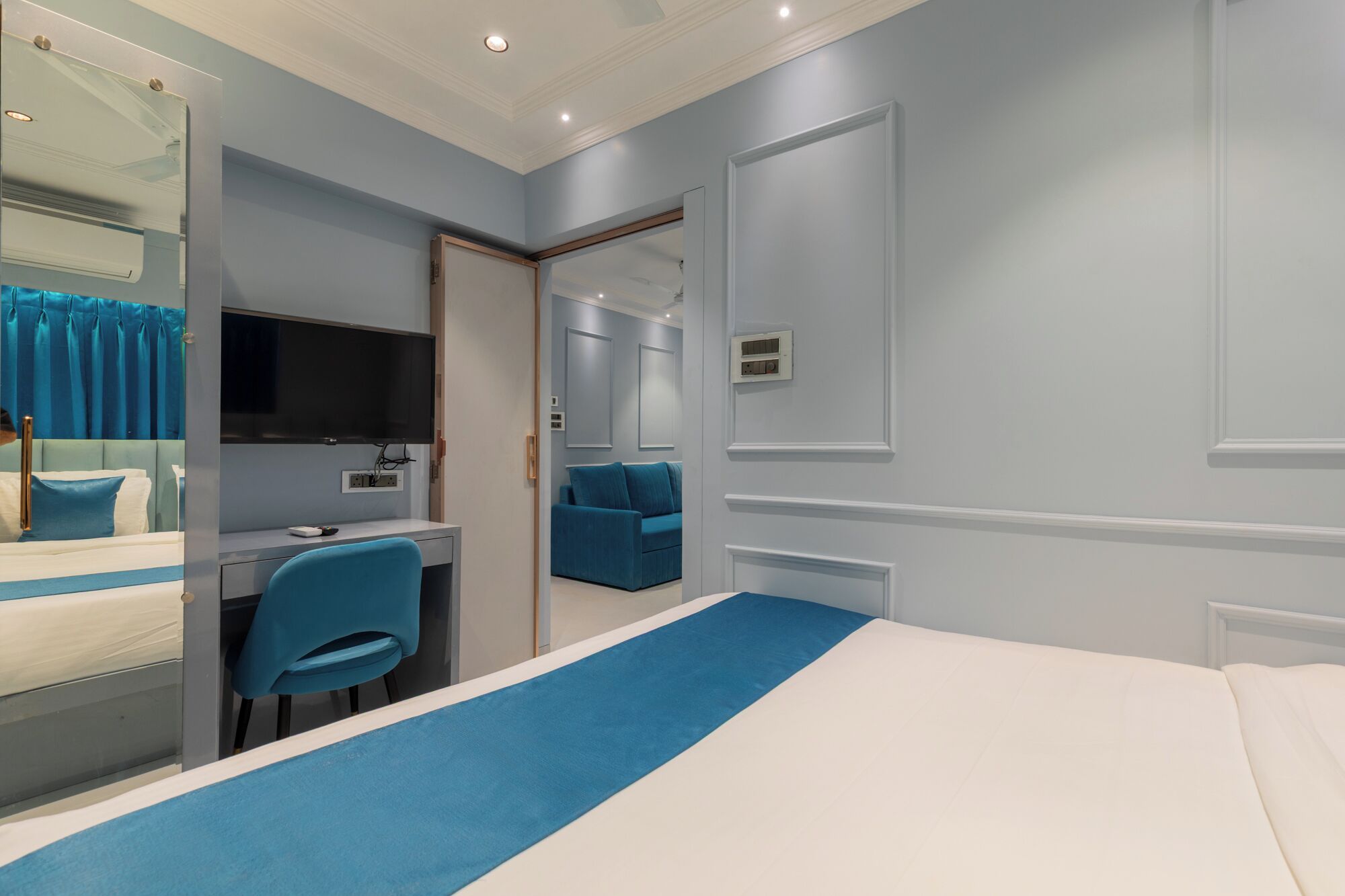 Une chambre d’hôtel avec un lit, un bureau et une chaise, une télévision et un miroir.